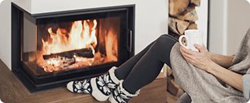 a person sitting in front of a fireplace holding a cup