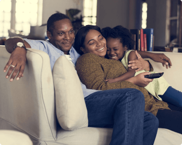 Parents and daughter on a couch watching tv together