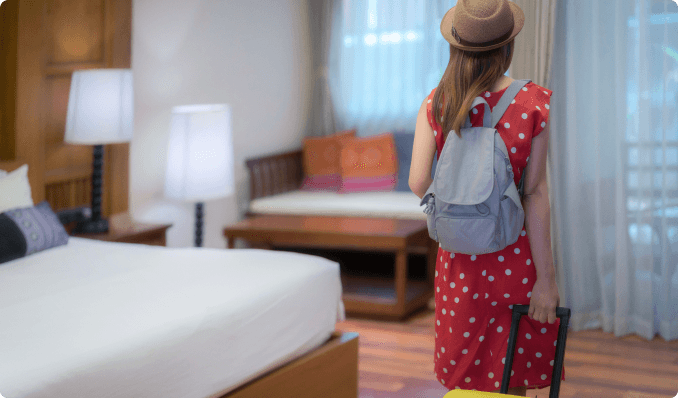 a woman bringing a suitcase into a hotel room