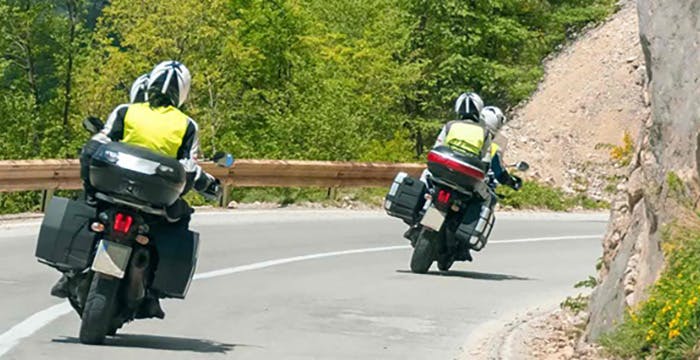 a couple of people ride motorcycles down a road